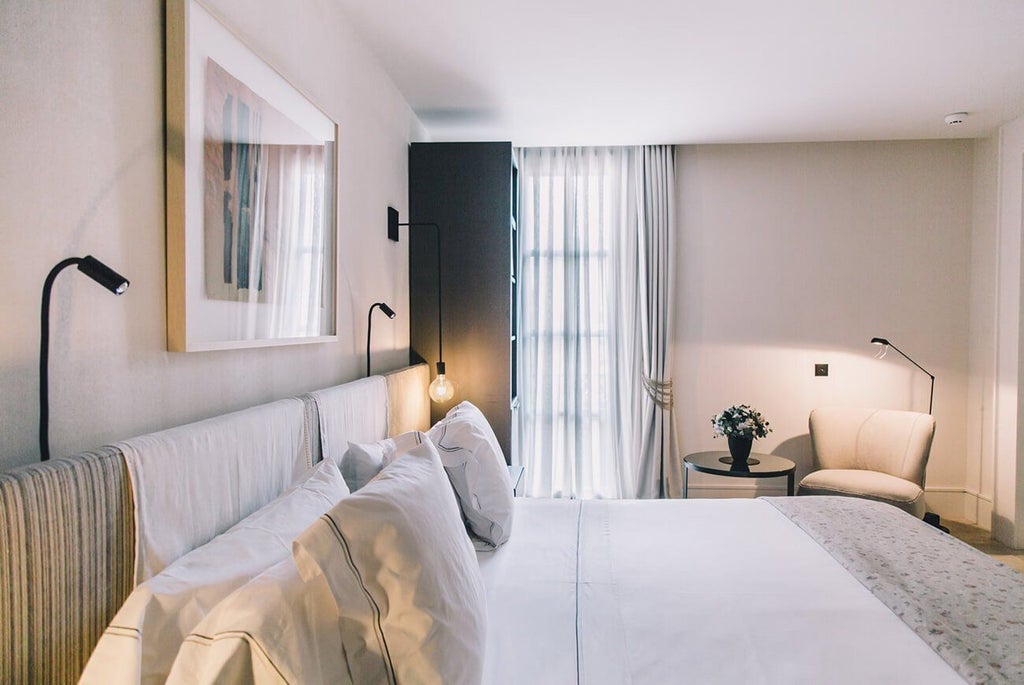 Luxurious deluxe hotel room at Sant Francesc Hotel Singular, featuring elegant minimalist design with white linens, modern furnishings, and soft natural lighting in Spain