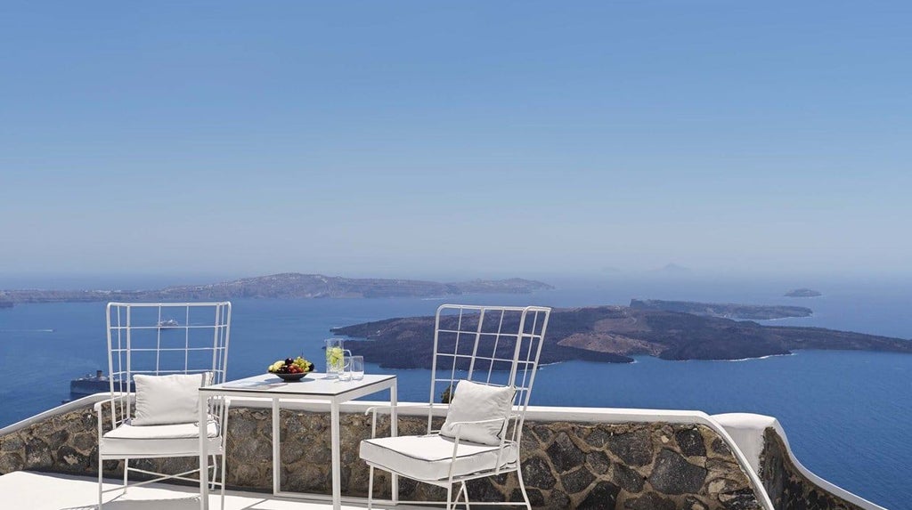 Luxury Santorini suite with private outdoor jetted tub overlooking white-washed Cycladic architecture and azure Aegean Sea horizon