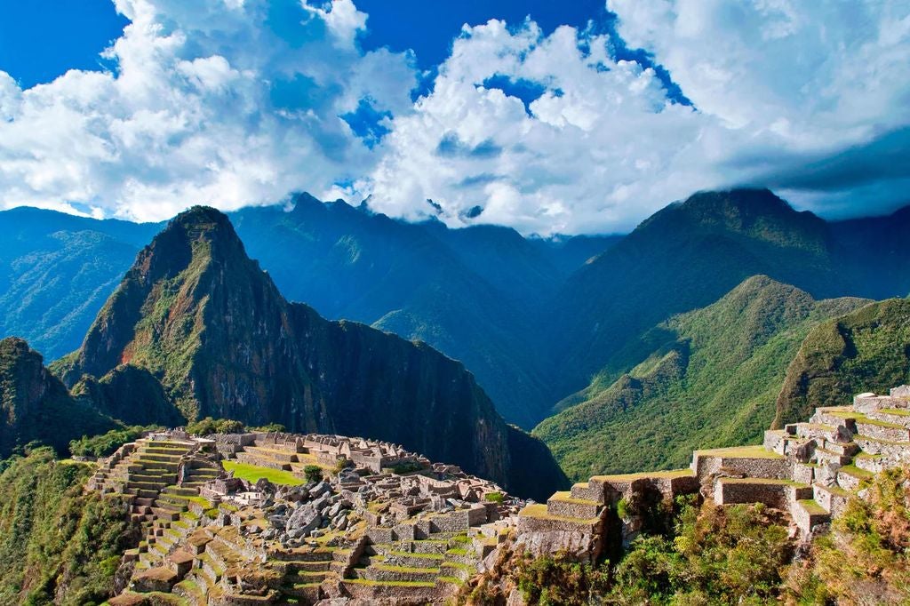 Luxury mountain resort with stone and glass facade nestled in Sacred Valley, reflecting pool in foreground, Andes peaks behind