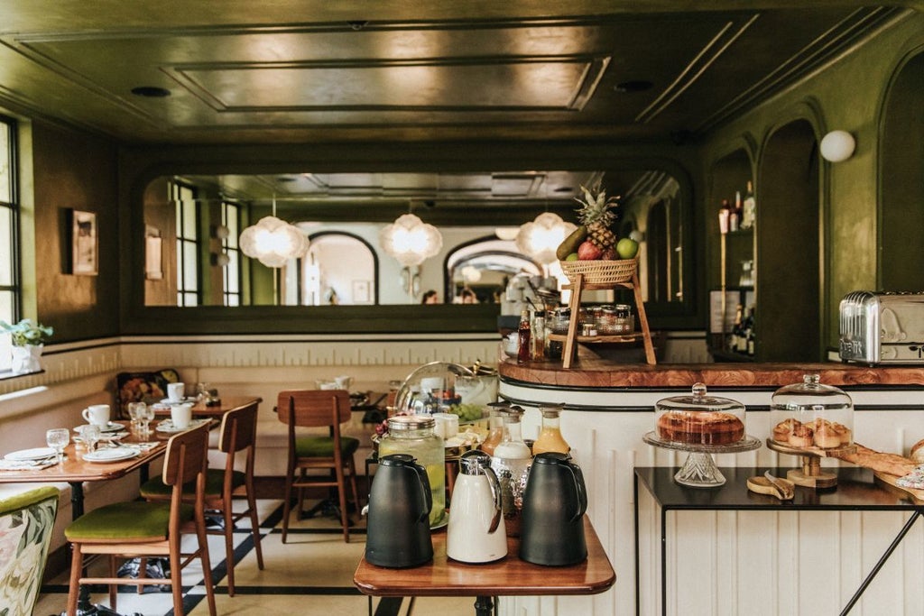 Elegant Parisian boutique hotel facade with soft pastel exterior, ornate wrought-iron balconies, and charming windows showcasing French architectural sophistication