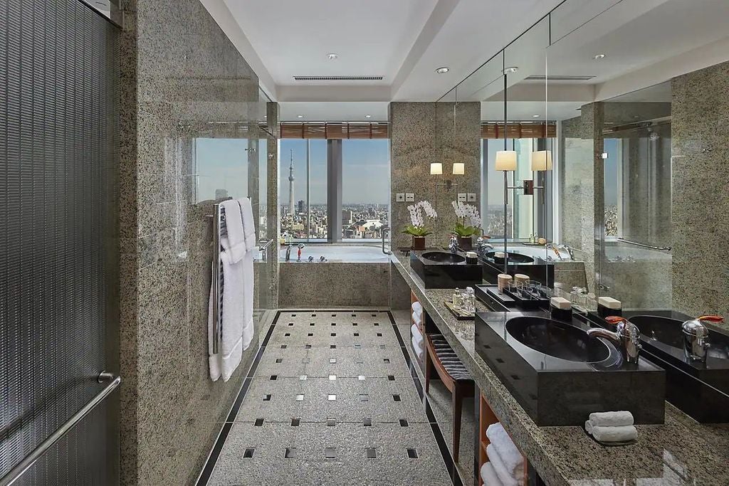 Luxurious corner suite with floor-to-ceiling windows offering panoramic Tokyo views, modern furnishings, and marble bathroom details