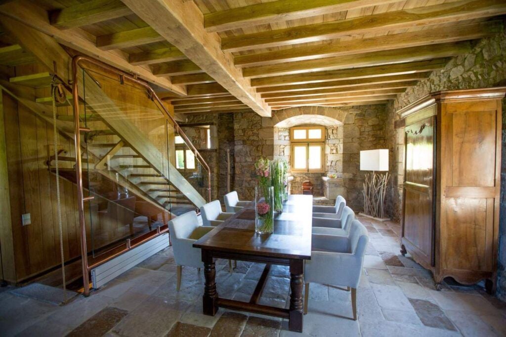 Luxurious French cottage bedroom with elegant wooden floors, soft neutral tones, and expansive windows overlooking scenic countryside at Domaine des Etangs