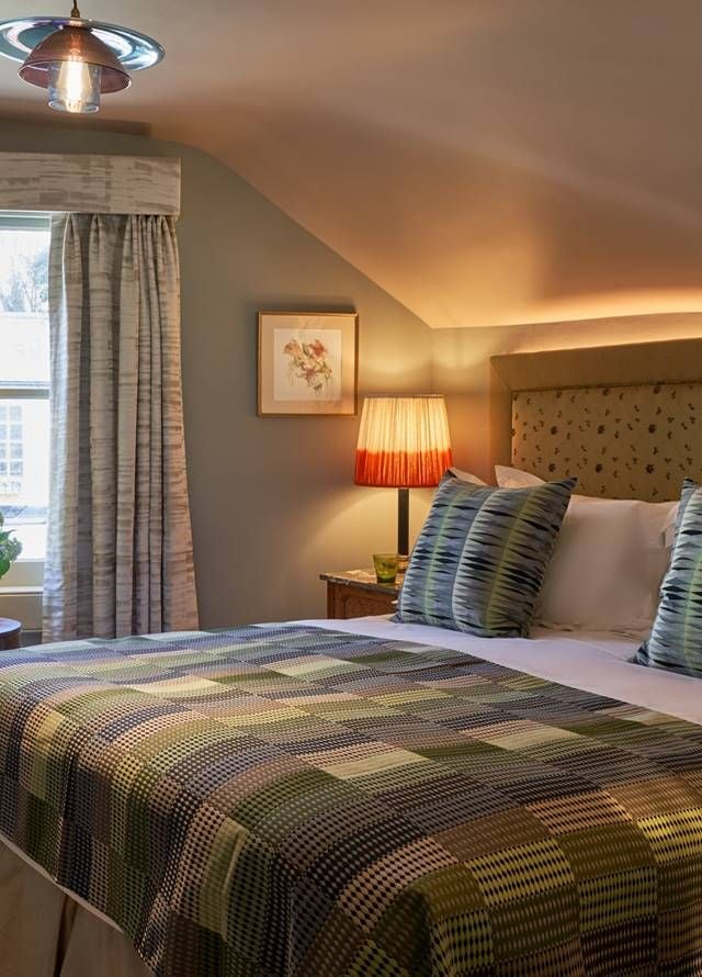 Elegant bedroom in modern boutique hotel, plush white bedding, soft neutral tones, minimal design with statement lighting and city-view window in United Kingdom