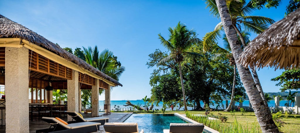 Luxurious open-air hotel lounge with wooden beams, tropical plants and ocean views through floor-to-ceiling windows in Madagascar