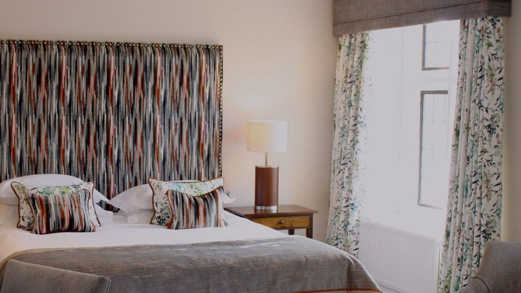 Elegant Mews Room at Bovey Castle Hotel, featuring plush bedding, classic British decor, and warm wooden furnishings in a luxurious country estate setting.