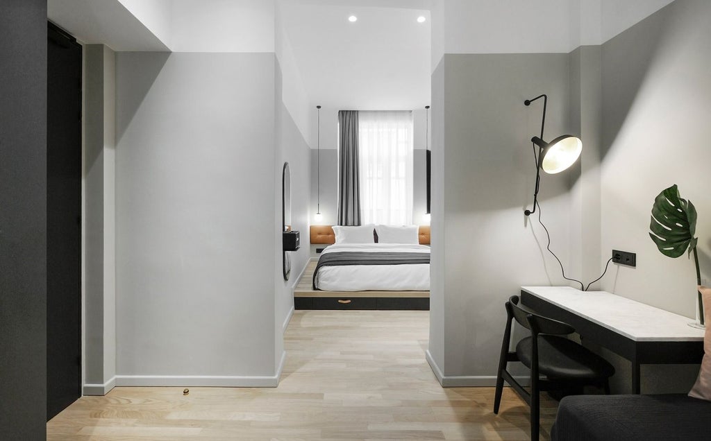 Spacious XL room with minimalist design, featuring sleek gray walls, modern furniture, and large windows overlooking urban scenery in Thessaloniki, Greece