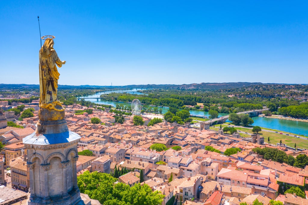 Medieval stone bridge and historic Papal Palace in Avignon, France, with sunlit limestone walls and elegant architectural details showcasing the city's rich cultural heritage