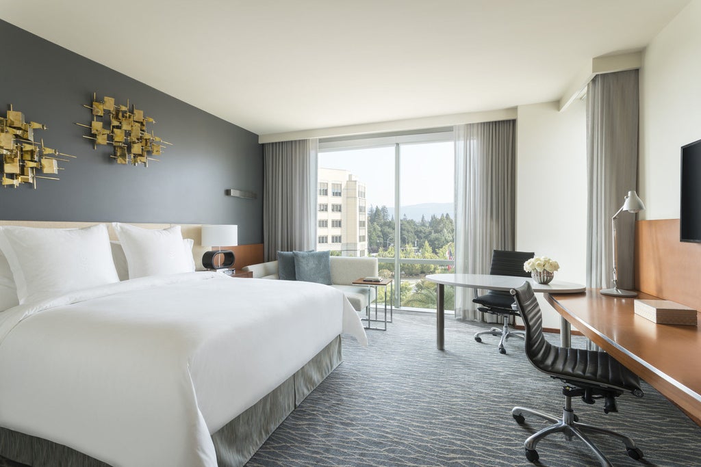 Modern luxury hotel exterior with glass facade, palm trees and dramatic lighting at dusk, showcasing contemporary architecture in Palo Alto