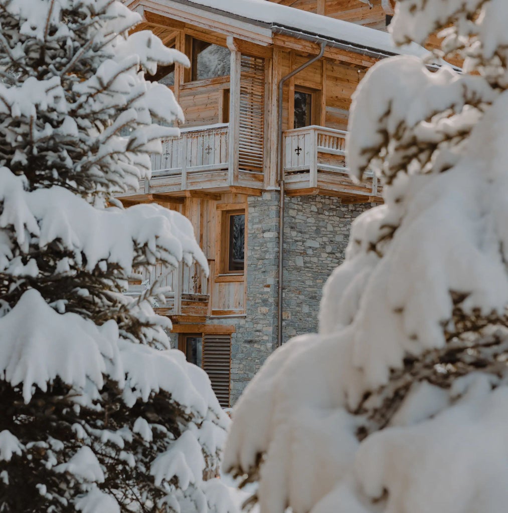 Luxurious alpine bedroom with panoramic mountain views, modern minimalist design, warm wooden accents, and elegant contemporary furnishings in Scenset Hotel Courchevel