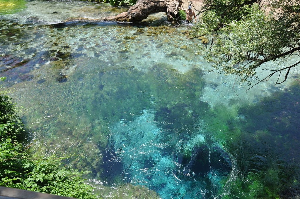 Turquoise Blue Eye Spring in Albania's lush landscape, with elegant dining setup featuring local cuisine against pristine natural backdrop