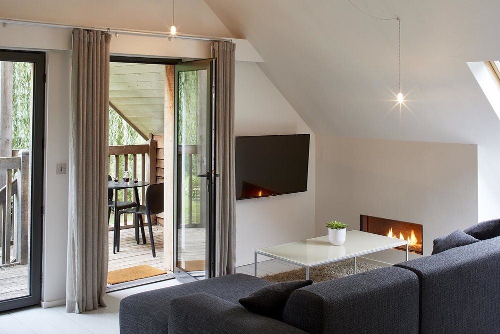 Luxurious loft suite with exposed wooden beams, contemporary furnishings, and soft natural light at Tuddenham Mill, showcasing modern rustic elegance