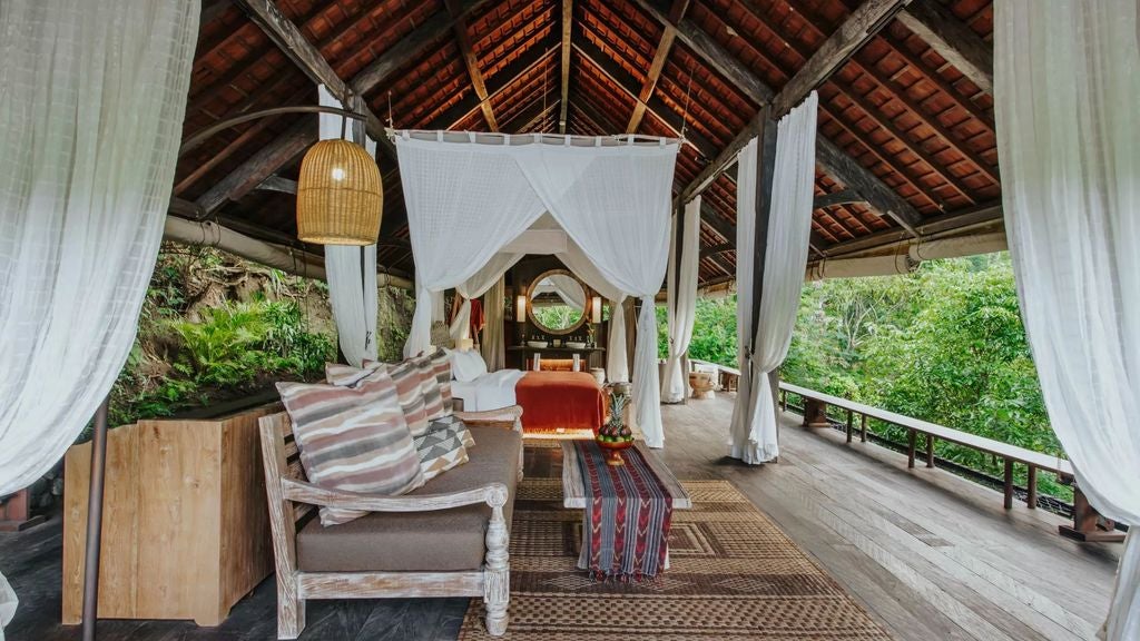 Luxurious open-air villa in Bali's jungle featuring infinity pool, wooden deck, and panoramic mountain views through bamboo architecture