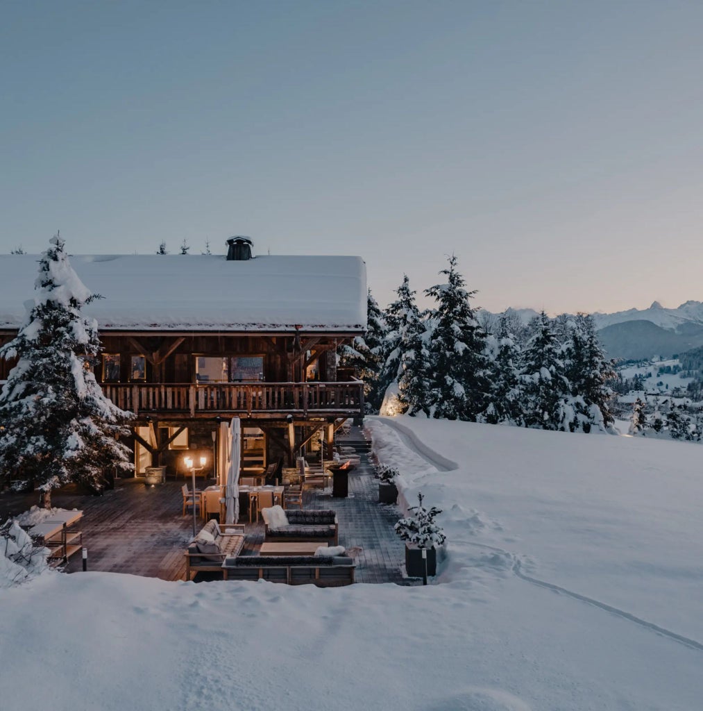 Luxurious chalet-style Scenset hotel nestled in snow-covered French Alps, featuring elegant alpine architecture with large windows and modern design elements