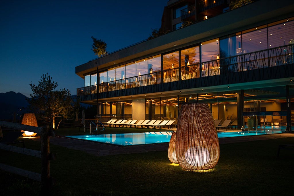 Luxurious modern wood and glass hotel nestled in alpine landscape, with floor-to-ceiling windows overlooking lush forests and mountain peaks in scenset, Italy