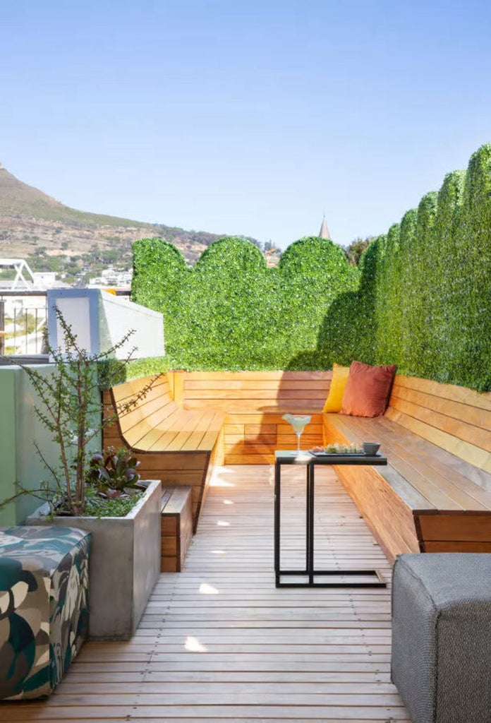 Modern luxury hotel exterior with glass balconies, white facade, and rooftop terrace overlooking Cape Town's cityscape at sunset