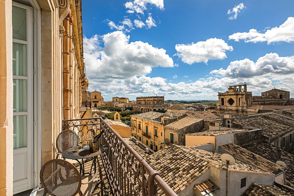 Elegant Sicilian boutique hotel with arched stone windows, soft terracotta walls, and lush garden overlooking historic Noto's baroque architecture