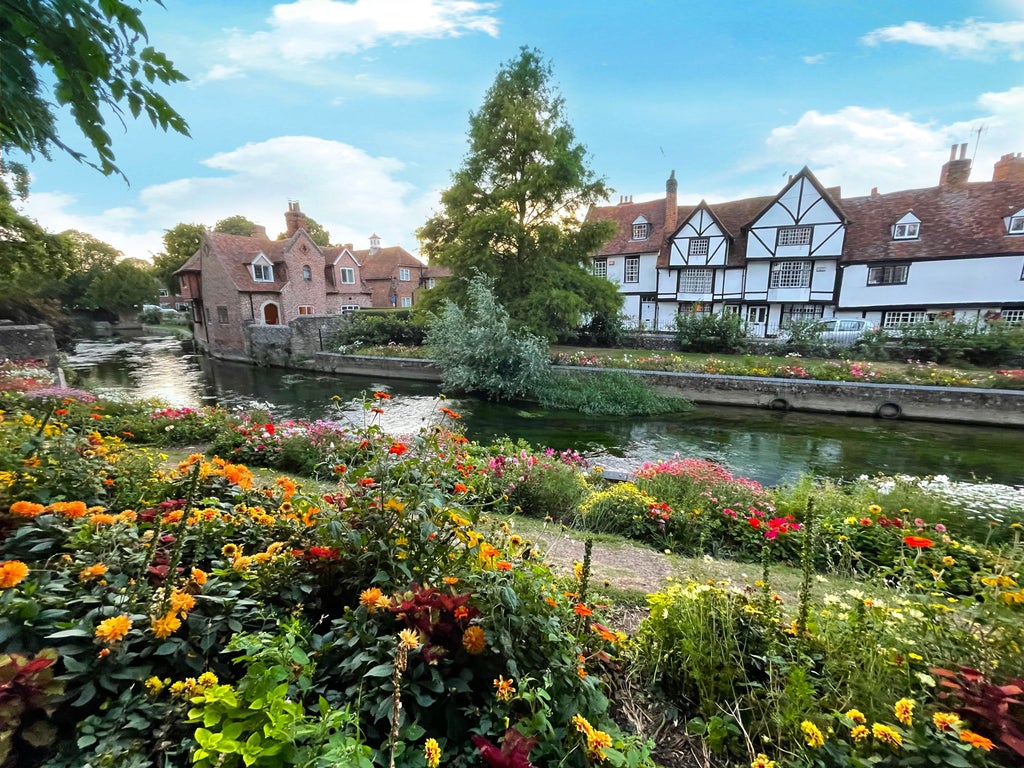 Historic Canterbury Cathedral's ornate Gothic towers and spires rising above medieval city walls, surrounded by autumn trees