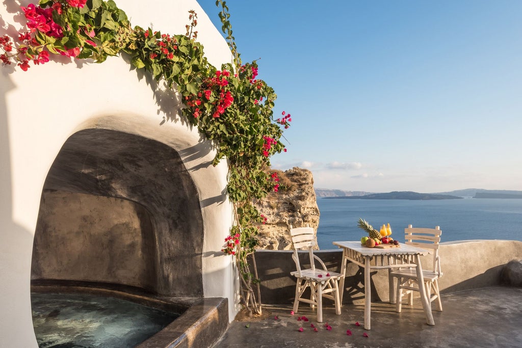 Elegant white-washed Greek villa with infinity pool overlooking Santorini caldera at sunset, featuring traditional Cycladic architecture