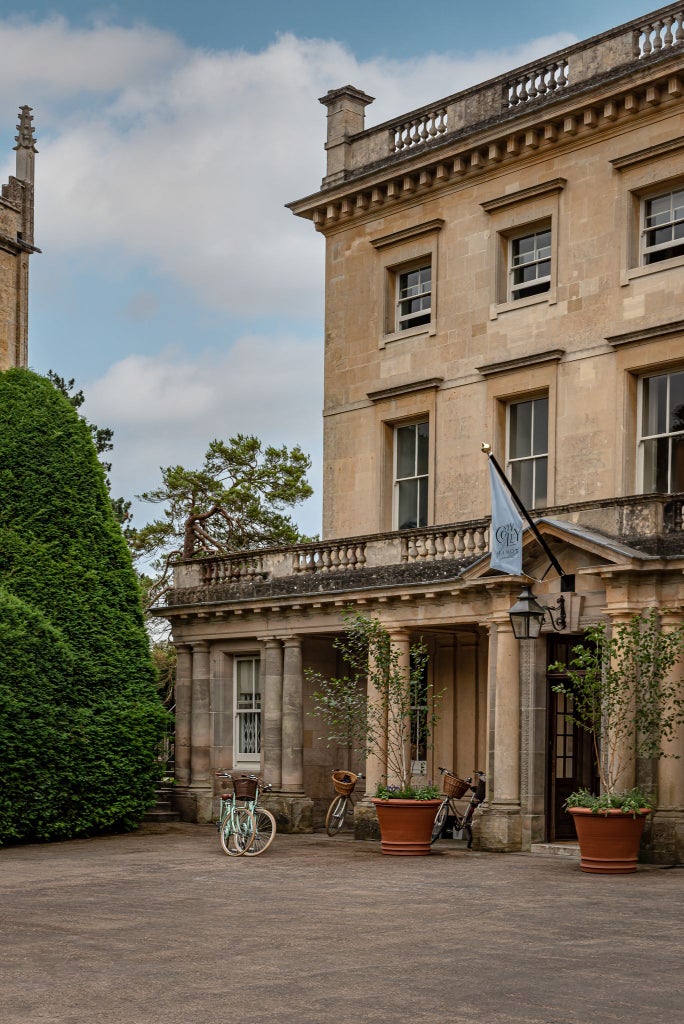 Luxurious countryside manor with contemporary design, featuring lush green gardens, modern architectural lines, and elegant stone facade set in scenic UK landscape