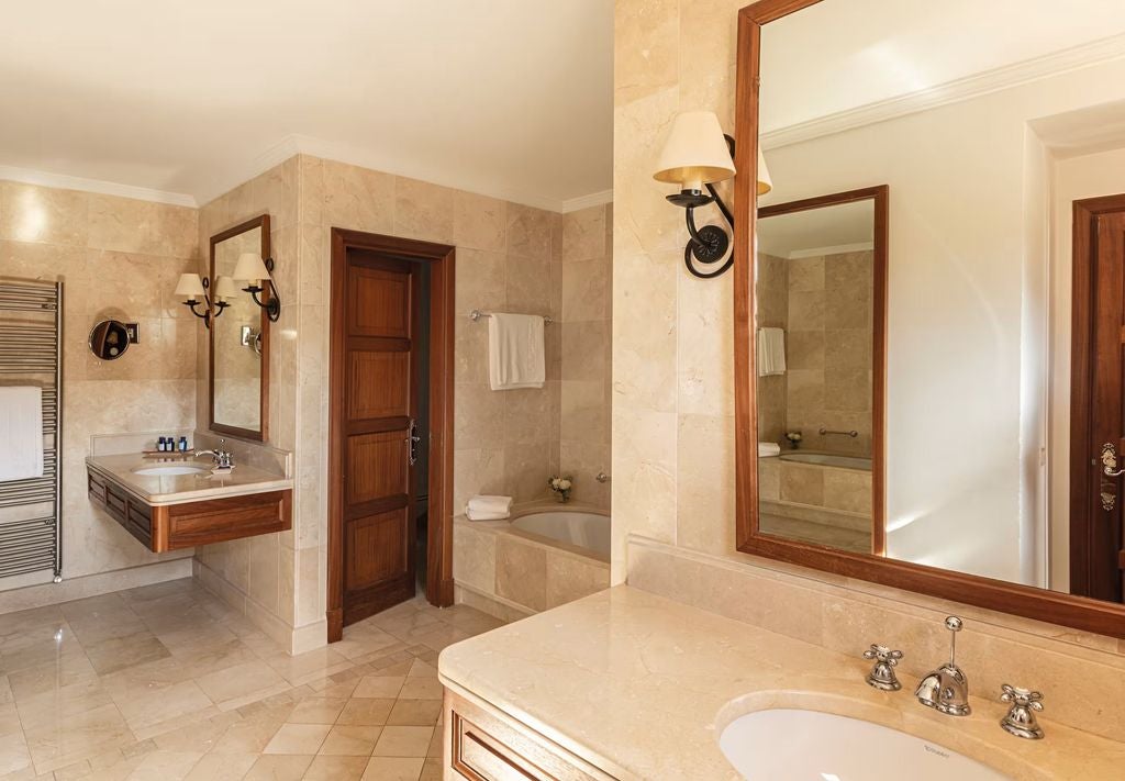 Elegant junior suite with stone walls, exposed wooden beams, and traditional Mallorcan decor featuring a king bed and seating area