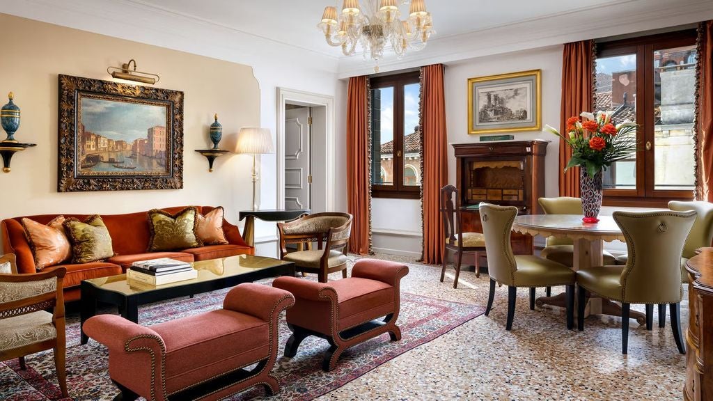 Opulent Venetian suite with ornate gold-framed mirrors, crystal chandelier, antique furniture, and plush damask upholstery in cream and blue tones