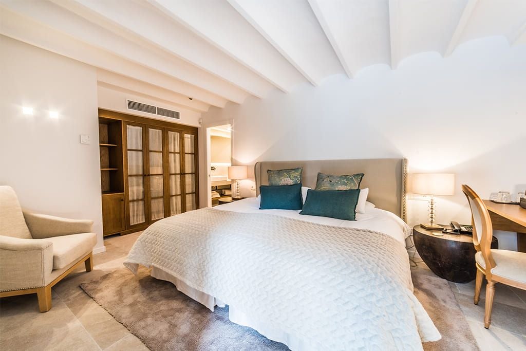 Spacious double garden room at L'Avenida Sóller hotel, featuring elegant white linens, minimalist decor, and soft natural lighting in Mallorca, Spain.