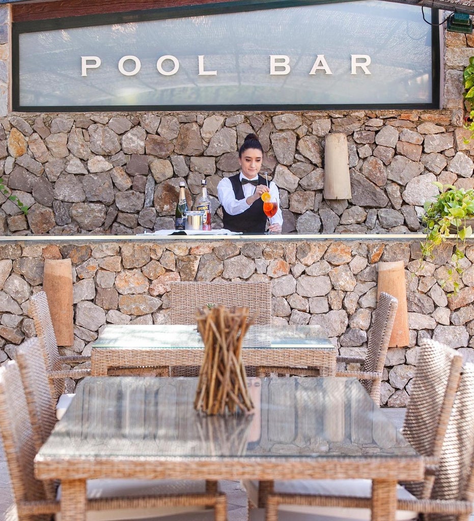 Elegant Mediterranean hotel with stone façade nestled in Mallorca hills, featuring arched windows and traditional Spanish architecture