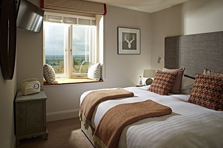 Spacious luxury suite with lake view, contemporary wooden furnishings, modern bathroom, and expansive floor-to-ceiling windows at The Fish Hotel in the Cotswolds.