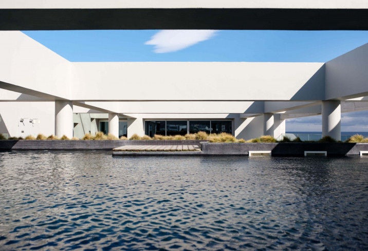 Modern five-star hotel with sleek glass facade and illuminated balconies overlooking the marina at sunset in Ponta Delgada, Azores