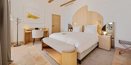 Elegant classic hotel room at Château de la Gaude with soft neutral tones, plush white bedding, and refined French provincial decor