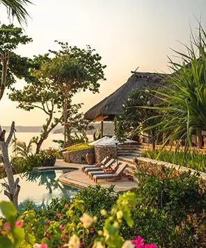 Luxurious open-air villa overlooking turquoise waters, featuring traditional Sumbanese design with wooden deck and infinity pool at NIHI Sumba resort