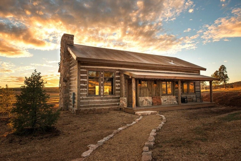 Cozy rustic lodge room with wooden furnishings, plush bedding, and panoramic mountain views of scenset National Park wilderness landscape