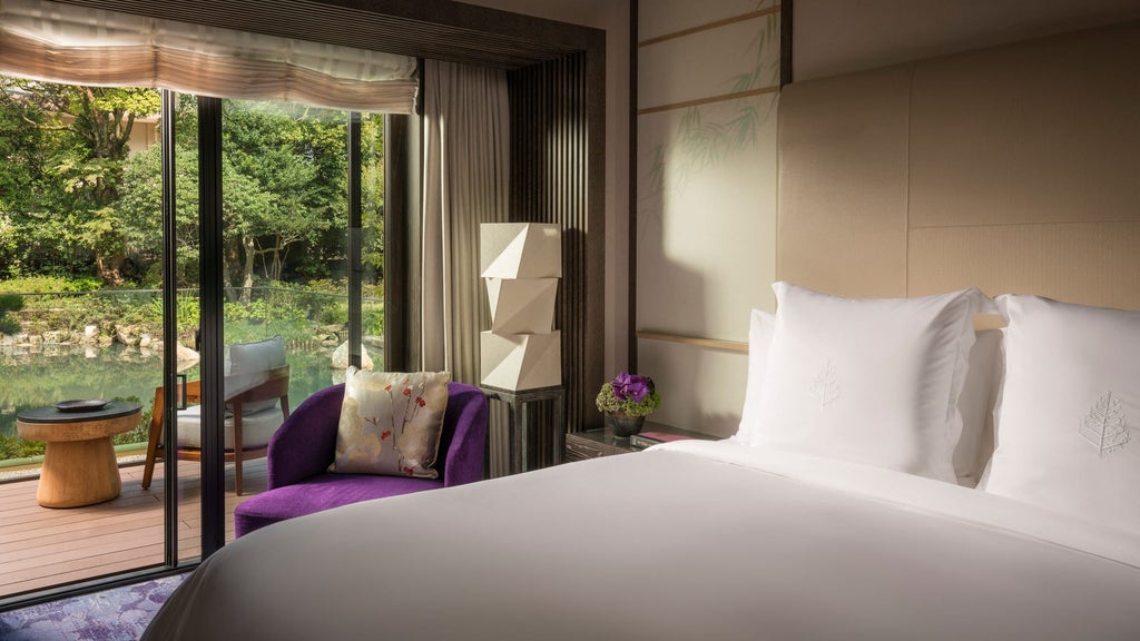 Elegant Japanese-inspired executive suite with silk panels, minimalist decor, king bed, and panoramic garden views at Four Seasons Kyoto