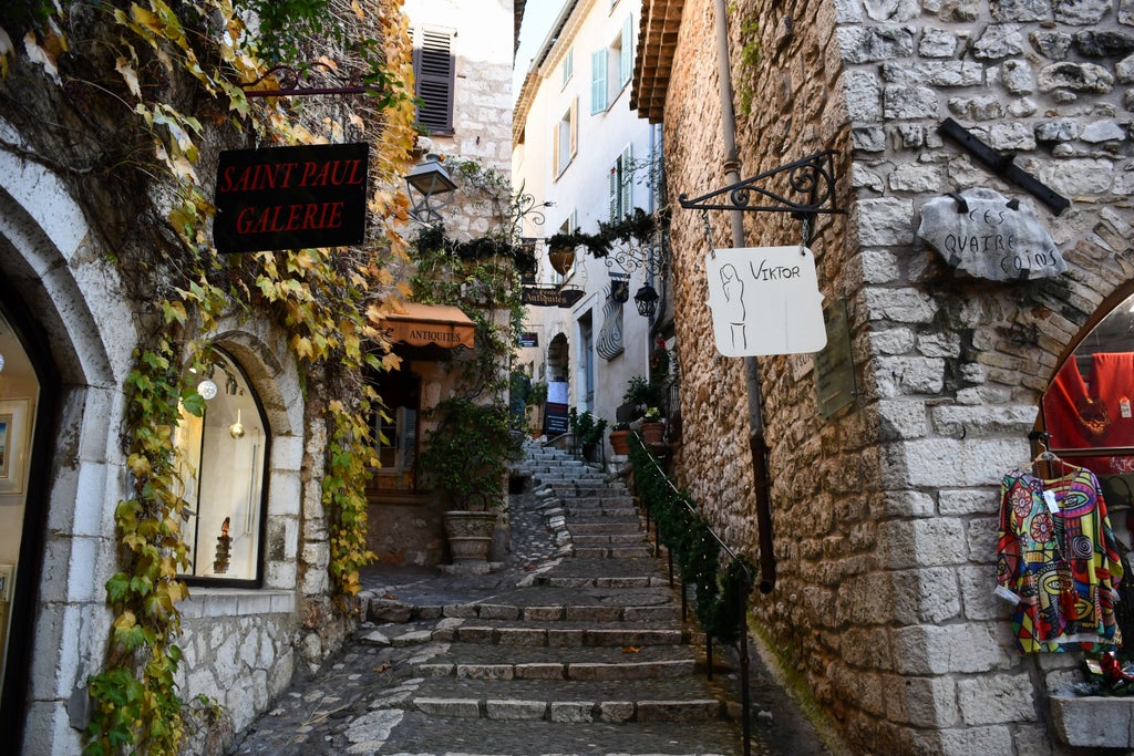 Quaint cobblestone alley in Saint-Paul-de-Vence with blooming flowers, stone archways and rustic Provence architecture under soft sunlight