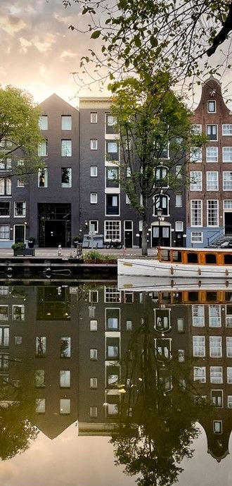 Historic canal houses seamlessly connected to form luxury Hotel Pulitzer Amsterdam, featuring elegant brick facades and traditional Dutch architecture