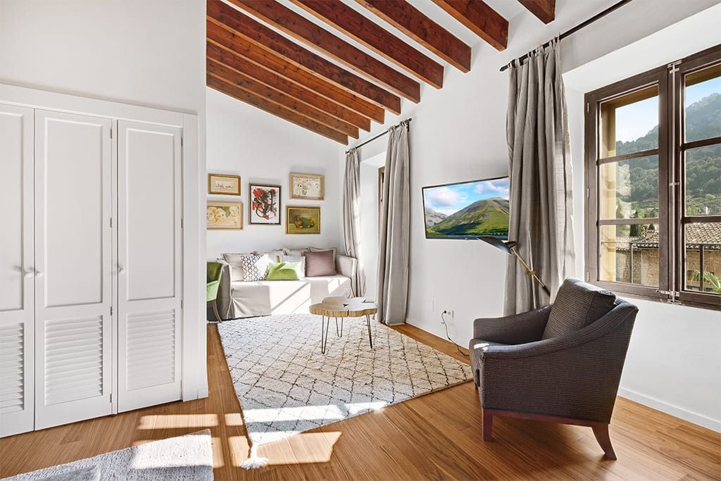 Elegant junior suite with plush white bedding, wooden accents, and large windows overlooking lush scenset landscape in a luxurious Spanish hotel room