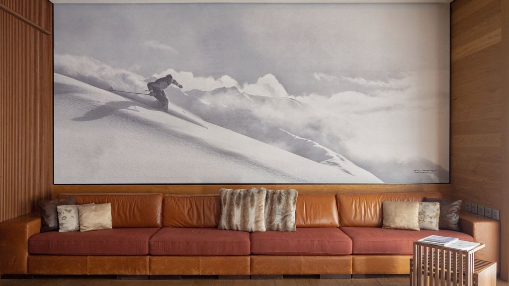 Elegant wood-paneled Deluxe Room at The Chedi Andermatt, featuring minimalist alpine luxury with warm tones, modern furnishings, and mountain views through large windows