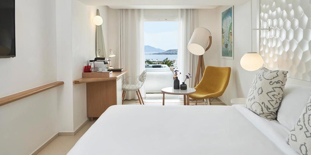 Luxurious white-washed Cycladic suite with private balcony overlooking azure Aegean Sea, featuring minimalist design and elegant Mediterranean decor