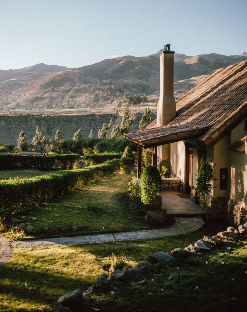 Luxurious stone villa with private terrace overlooking Sacred Valley mountains, featuring traditional Peruvian architecture and manicured gardens