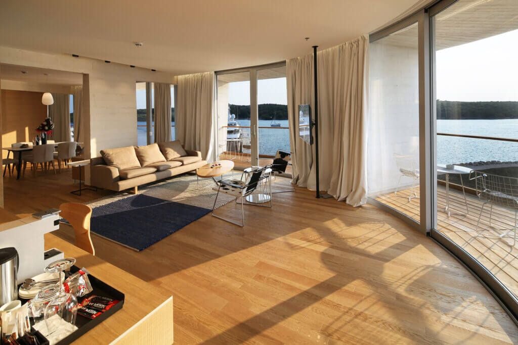 Spacious presidential suite with panoramic sea view, elegant wood furnishings, plush king bed, and floor-to-ceiling windows overlooking Šibenik coastline