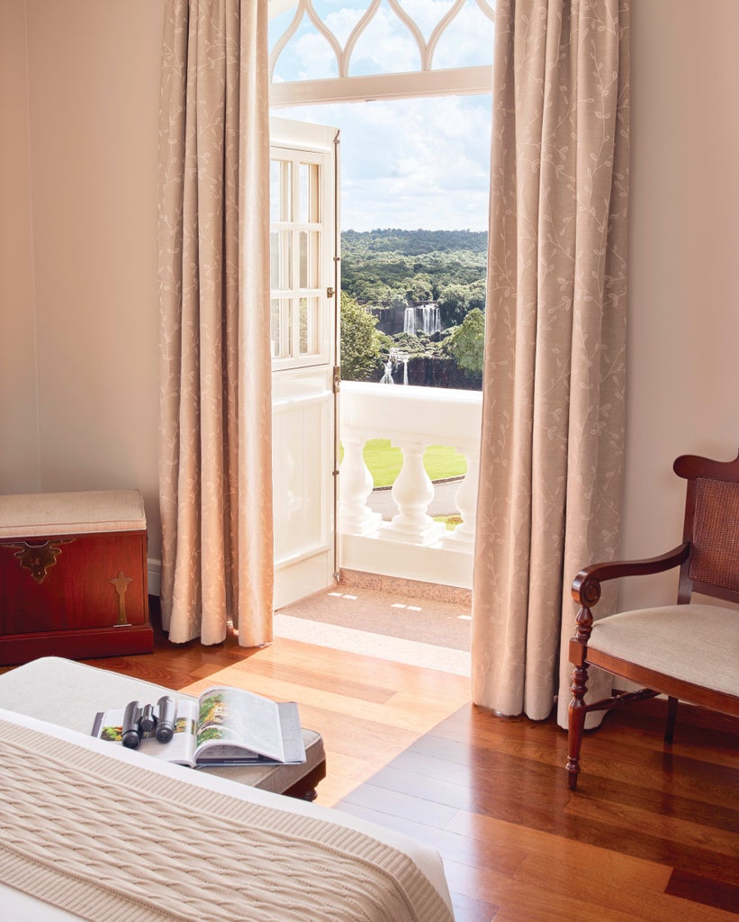 Pink-hued luxury colonial hotel with grand arches and balconies surrounded by lush tropical gardens at sunset near Iguazu Falls