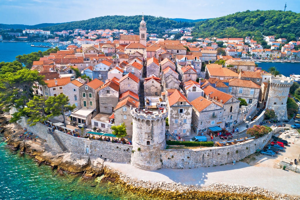 Tour group exploring charming cobblestone streets of Korčula old town, with historic stone buildings and medieval fortifications at sunset