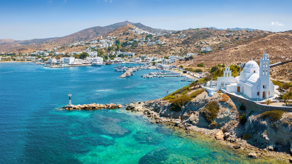 Sunset-lit Cycladic white-washed taverna terrace overlooking azure Aegean Sea, with elegant table setting and traditional Greek culinary delicacies