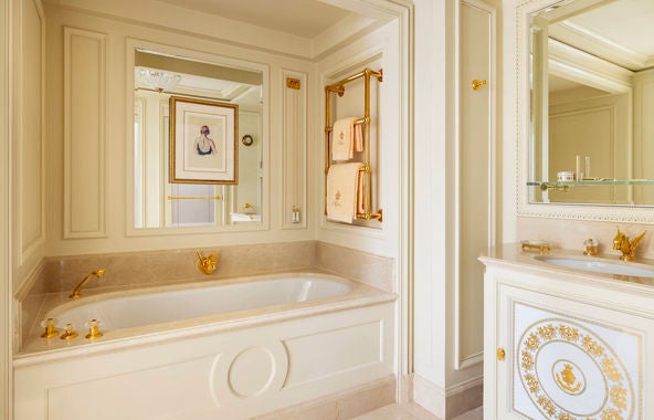 Elegant Superior Room at Ritz Paris featuring period furniture, crystal chandelier, gold-framed mirrors, and luxurious silk drapes in cream and gold