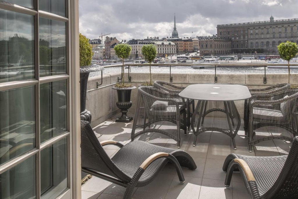 Elegant five-star hotel with classic Nordic architecture, featuring grand waterfront balconies, ornate white facade and panoramic Stockholm views