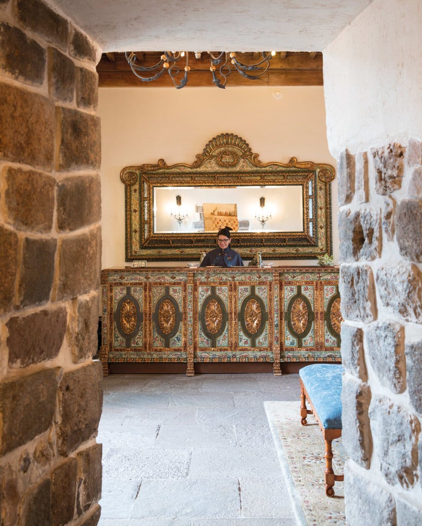 Elegant colonial courtyard of luxury Peruvian hotel with stone archways, manicured gardens and peaceful reflection pool at sunset