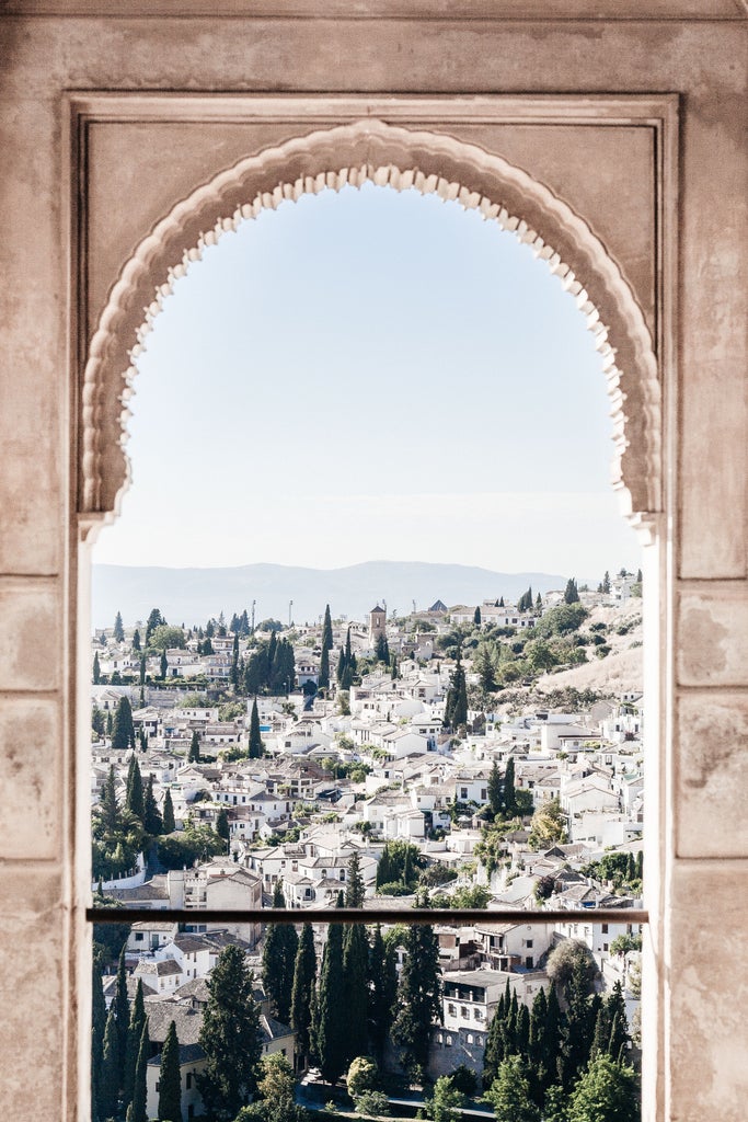 Intricate Moorish architecture of Alhambra's Palace of Lions, golden sunlight illuminating ornate arches and marble fountains in Granada's historic landmark