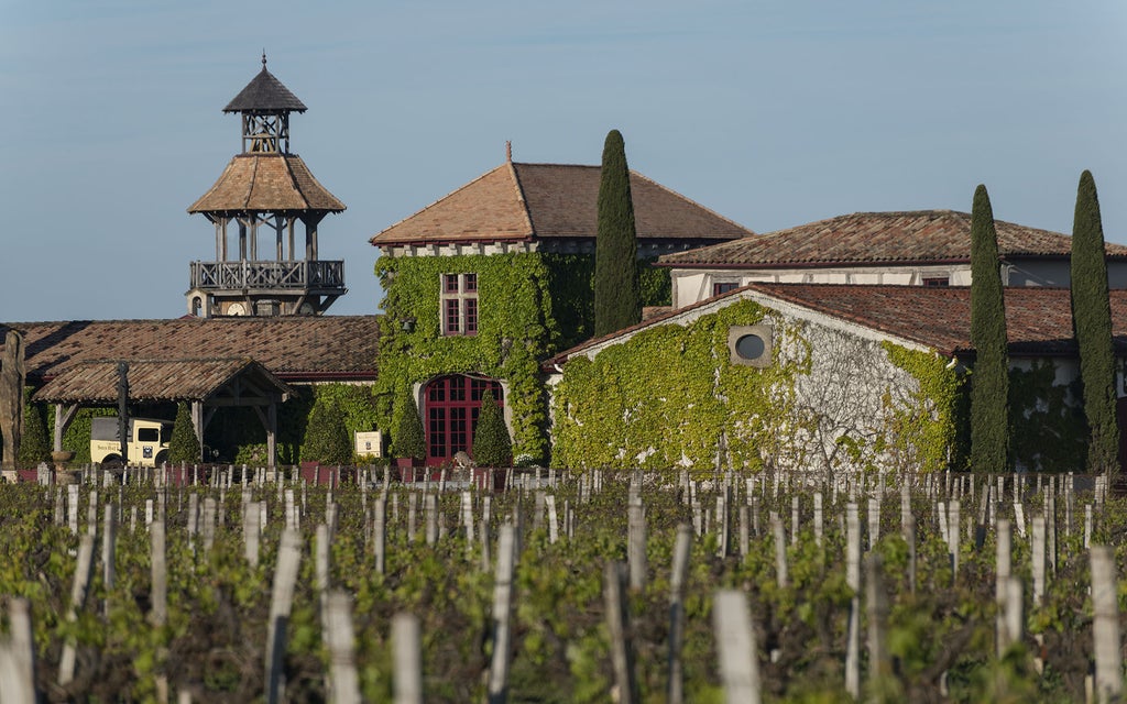 Elegant French chateau-style spa hotel nestled among vineyards, featuring stone walls, terracotta roof tiles and serene lake views