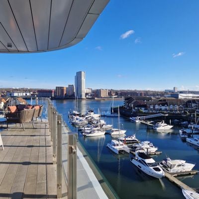 Elegant waterfront hotel with modern glass facade, overlooking Southampton harbor, showcasing contemporary luxury and maritime charm at dusk