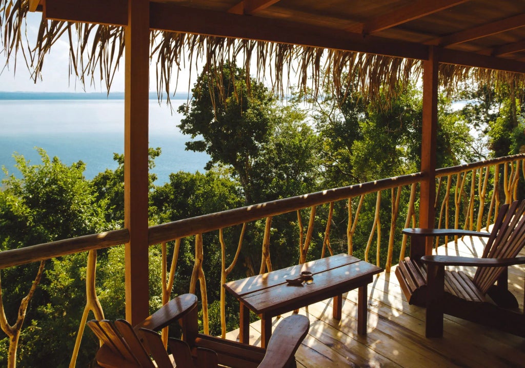 Elegant boutique hotel room with rustic wooden furniture, soft white linens, and expansive windows overlooking lush Argentine landscape at La Lancha